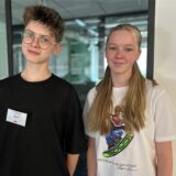 Ein Junge und ein Mädchen, die vor einem Fenster stehen.