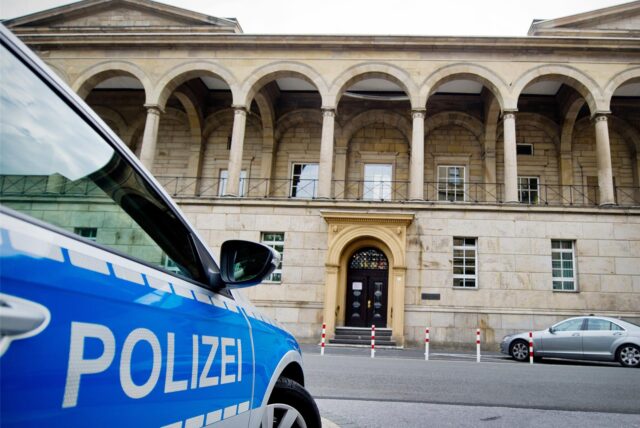 Vorderansicht eines Landgerichts. Davor steht ein Streifenwagen der Polizei.