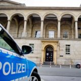 Vorderansicht eines Landgerichts. Davor steht ein Streifenwagen der Polizei.