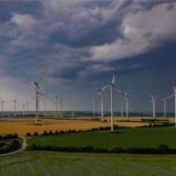 Dunkle Wolken einen nahenden Gewitters ziehen am frühen Morgen über die Landschaft mit einem Windenergiepark im Osten von Brandenburg