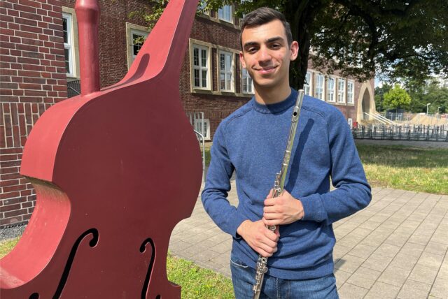 Elnur Misirli steht mit einer Querflöte in der Hand vor der Hertener Musikschule.