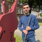 Elnur Misirli steht mit einer Querflöte in der Hand vor der Hertener Musikschule.