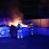 Feuerwehrleute löschen einen brennenden Container auf einem Sammelplatz.