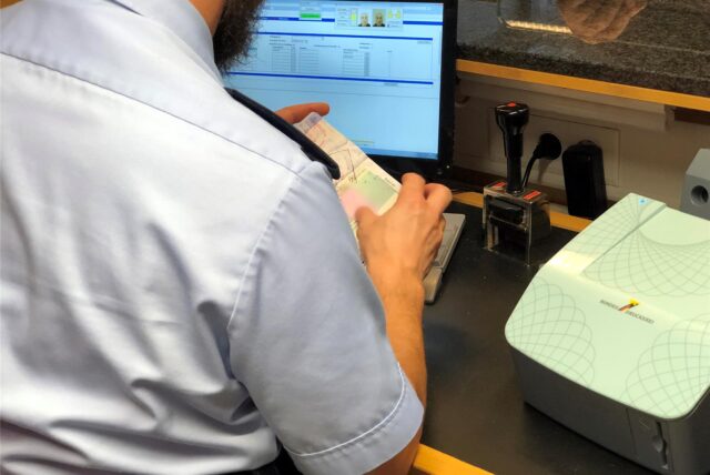 Ein Bundespolizist am Dortmunder Flughafen kontrolliert einen Reisepass.
