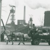 Ein Altwarenhändler mit Pferdefuhrwerk vor der Kulisse der Zeche Erin in Castrop-Rauxel.