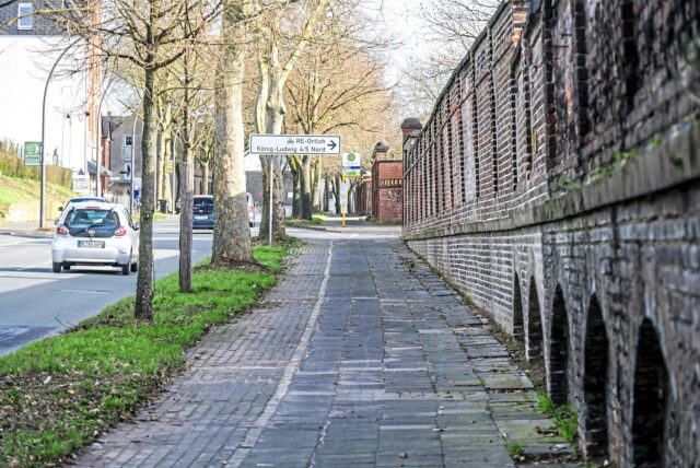Gehweg neben einer alten Zechenmauer an der Suderwichstraße in Recklinghausen. Im Hintergrund ist ein Hinweisschild für die Zufahrt zum Gewerbegebiet RE-Ortloh König-Ludwig 4/5 Nord zu sehen. (Archivbild)