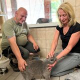 Lars Riedel und Conny Lehmann knien nebeneinander und streicheln eine Katze.