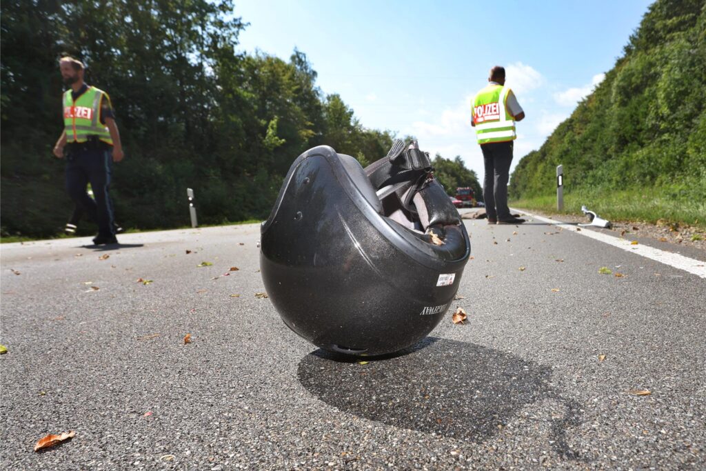 Polizisten arbeiten an einer Unfallstelle, auf der Straße liegt ein Motorradhelm Polizisten arbeiten an einer Unfallstelle, auf der Straße liegt ein Motorradhelm
