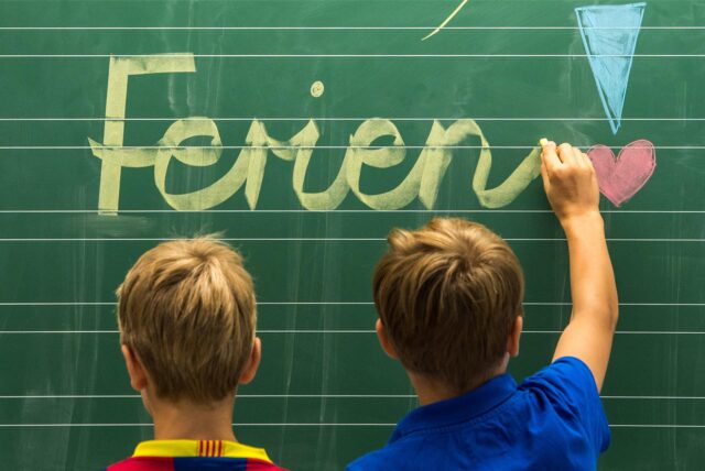 Drittklässler einer Grundschule in Straubing (Niederbayern) schreiben am 31.07.2012 «Schöne Ferien!» auf eine Tafel in einem Klassenzimmer.