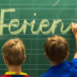 Drittklässler einer Grundschule in Straubing (Niederbayern) schreiben am 31.07.2012 «Schöne Ferien!» auf eine Tafel in einem Klassenzimmer.