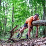 Ralf Nickel aus Recklinghausen liegt im Wald auf einem umgekippten Baumstamm.