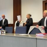 Die angeklagten Eltern (Mitte) an der Seite ihrer Verteidiger kurz vor Prozessbeginn am Landgericht Dortmund.