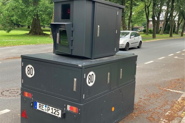 Eine semistationäre Geschwindigkeitsmessanlage steht auf der Hafenstraße in Datteln. Im Hintergrund fährt ein silberner Kleinwagen.