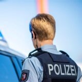 Eine Polizistin steht vor einem Streifenwagen, dessen Blaulicht leuchtet.