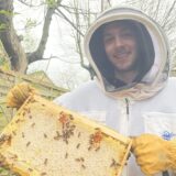 Micky Cassano hält eine Honigwabe mit Bienen darauf in die Kamera.