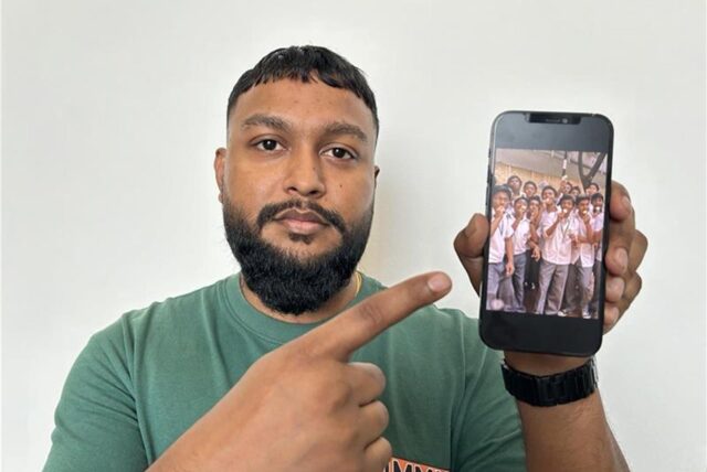 Ein Mann hält ein Smartphone in der Hand und zeigt auf ein Foto.