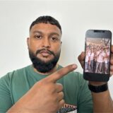 Ein Mann hält ein Smartphone in der Hand und zeigt auf ein Foto.