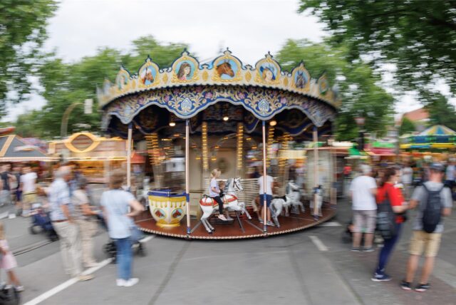 Eltern und Kinder stehen vor einem Kinderkarussell auf dem „Libori“