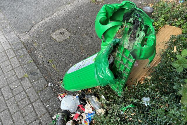 Ein verschmorter Mülleimer mit Unrat darunter.