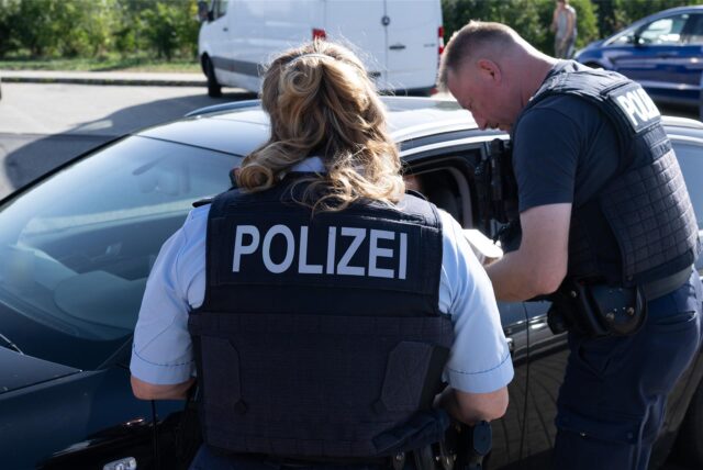 Zwei Polizisten kontrollieren einen Autofahrer (Symbolbild)