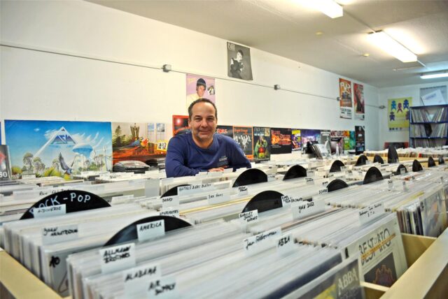 Ein Mann steht hinter Schallplatten.