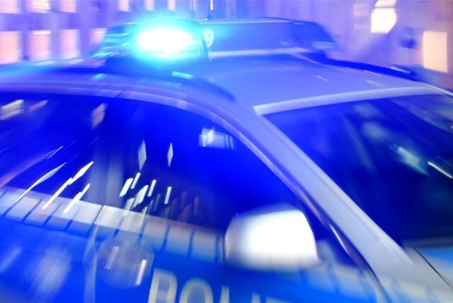 Ein Streifenwagen der Polizei steht mit eingeschaltetem Blaulicht auf der Straße. I