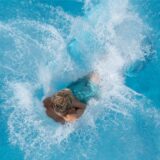 Ein Junge springt im Freibad vom 5-Meter-Turm ins Wasser (Archivbild).
