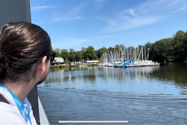 Ein braunhaariger Mann schaut auf Segelboote auf einem See