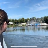 Ein braunhaariger Mann schaut auf Segelboote auf einem See