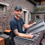Der Hertener Dachdeckermeister Raphael Soler Lopez hält einen Dachziegel in der Hand.