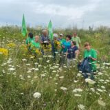 Mitglieder des BUND stehen auf einer Blumenwiese.