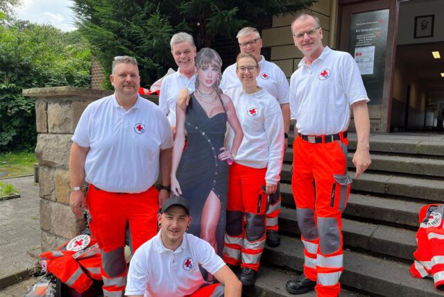 Gruppenfoto von DRK-Helfern mit einem Pappschild von Taylor Swift.