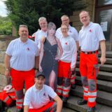 Gruppenfoto von DRK-Helfern mit einem Pappschild von Taylor Swift.