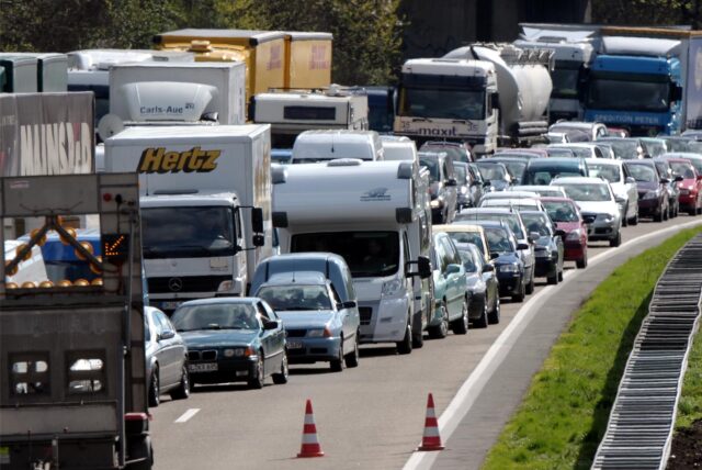 Ein Stau auf einer Autobahn: Hier wird von drei auf zwei Fahrspuren reduziert. Im Vordergrund ist die Absperrung der dritten Spur zu erkennen.