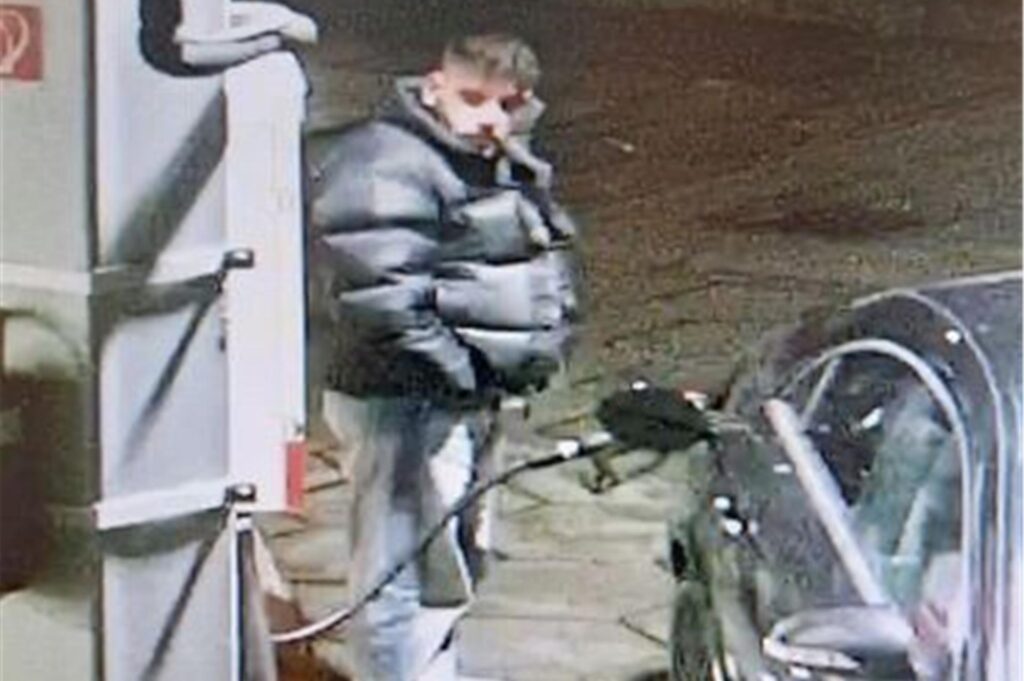 Ein Mann mit einer schwarzen Winterjacke und einer hellblauen Jeanshose steht an einer Tankstelle. Ein Mann mit einer schwarzen Winterjacke und einer hellblauen Jeanshose steht an einer Tankstelle.