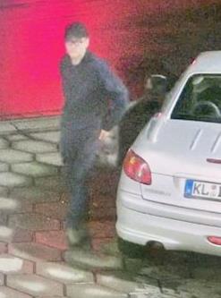 Ein dunkel gekleideter Mann steht neben einem silbernen Auto. Ein dunkel gekleideter Mann steht neben einem silbernen Auto.