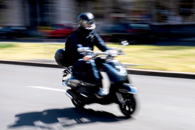 Ein Mann fährt auf einem Motorroller.