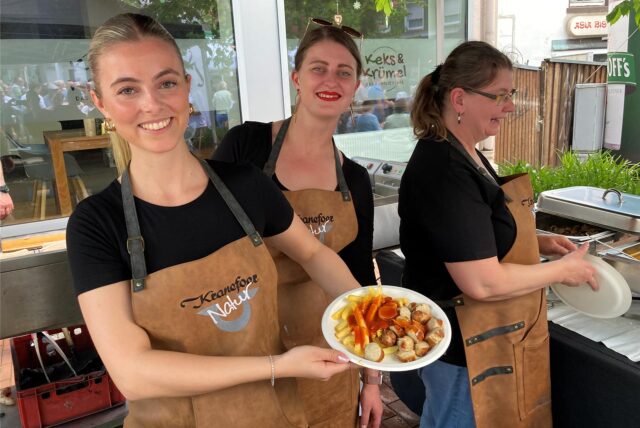 Die Geschwister Kranefoer zeigen einen Currywurst-Teller.