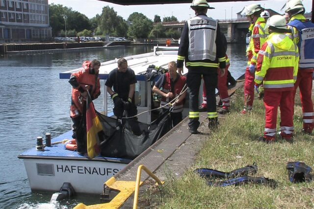 Feuerwehrleute stehen am Hafenbecken in Dortmund.