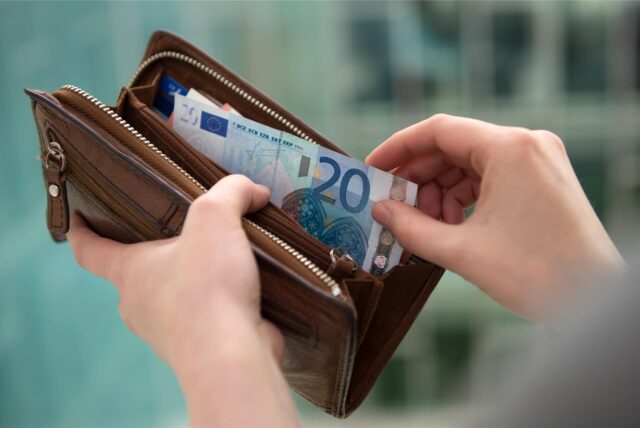 Eine Hand greift Geldscheine aus einem Portemonnaie