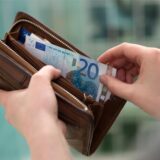 Eine Hand greift Geldscheine aus einem Portemonnaie