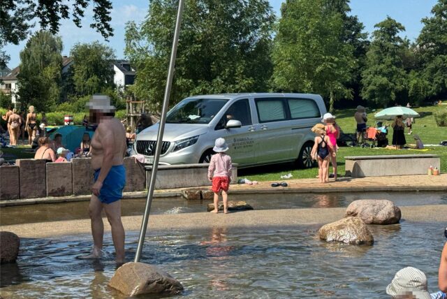Kinder stehen vor einem Leichenwagen im Freibad Froschloch.