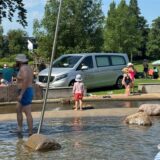Kinder stehen vor einem Leichenwagen im Freibad Froschloch.