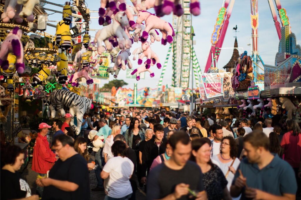 Blick auf zahlreiche Besucher der Cranger Kirmes in Herten, die zwischen den Buden und Fahrgschäften entlang bummeln.