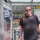 Carsten Engels steht frustriert an einer Bushaltestelle in Dortmund.