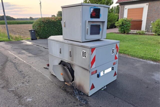 Ein hellgrauer Panzerblitzer am Straßenrand in Herten-Scherlebeck mit deutlich sichtbaren Brand- und Rußspuren.
