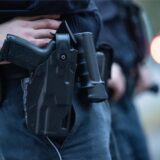 Ein Polizist steht bei einem Fototermin mit seiner Dienstwaffe an einer Straße (gestellte Szene). Nachdem er einen Schuss aus seiner Dienstwaffe bei einem Bundesligaspiel in Augsburg abgegeben haben soll, muss ein Polizist ab 20. August vor Gericht.