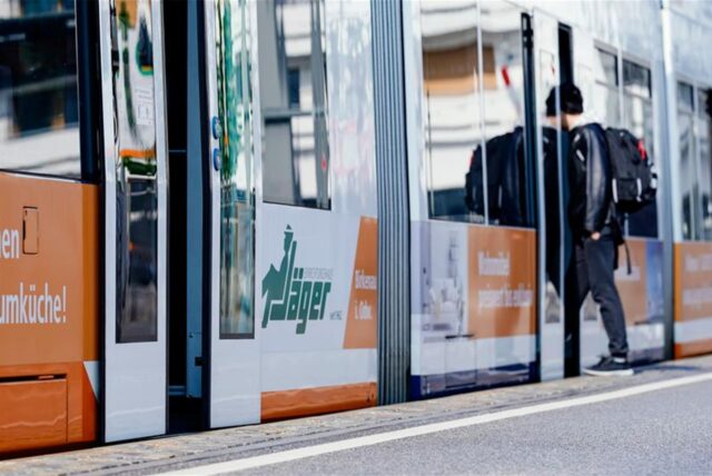 Ein junger Mann steigt an einer Straßenbahnhaltestelle in eine Straßenbahn ein.