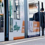 Ein junger Mann steigt an einer Straßenbahnhaltestelle in eine Straßenbahn ein.