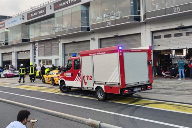 Feuerwehrleute laufen vor Box 27 in der Boxengasse des Nürburgrings.